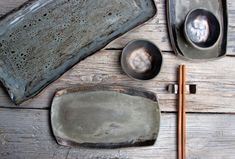 an assortment of silverware and chopsticks on a wooden table