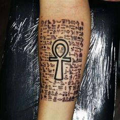 an egyptian tattoo on the arm with symbols and letters written in black ink above it