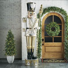 a nutcracker standing in front of a door with a wreath on the side