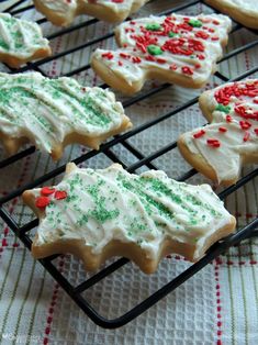 several decorated cookies on a cooling rack with red and green sprinkled icing