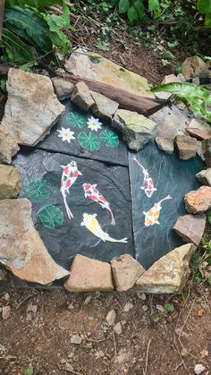 a rock garden with painted koi fish on it's sides and leaves around the edges