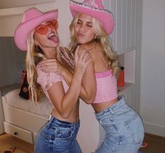 two beautiful young women wearing pink hats standing next to each other in front of a bed