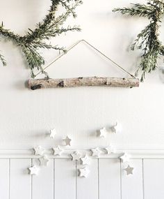 some white stars are hanging on the wall next to a branch and other decorations that look like branches