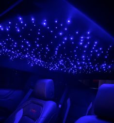 the interior of a car is lit up with blue lights and stars on the ceiling