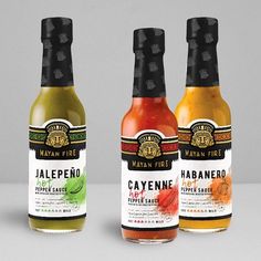 three bottles of jalepeno, cayenne and pepper sauce on a white surface