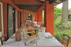 an outdoor dining area with table, chairs and fruit on the table in front of it