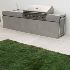 an outdoor bbq and grill in the grass next to a wall with a sink