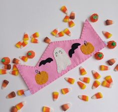 candy candies are scattered around a pink felt trick bag with a ghost on it