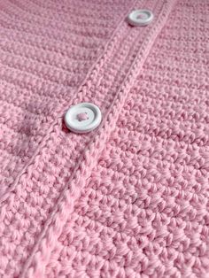 a pink knitted blanket with buttons on it