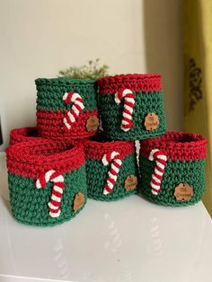 crocheted christmas baskets with candy canes and candies on them sitting on a table