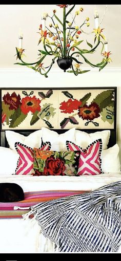 a bed with colorful pillows and a chandelier hanging above it's headboard