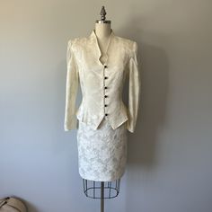 A lovely cream colored two piece 80s suit in great condition! Has two discoloration marks. One on skirt and one on back of shoulder. See I'm ages. The blouse closes with buttons down the front and ties tighter at the back of waist. A zipper runs down the back of the skirt.  Size: S/M Tag - Savannah Era - 80s  Material - cotton, acetate, polyester, plastic buttons, nylon zipper, chiffon Blouse: Bust -  Waist -  Arm length -  Length -  Skirt: Waist -  Hips -  Length -  Washing - lightly steam clea Cream Long Sleeve Skirt Suit For Formal Occasions, Fitted Long Sleeve Skirt Suit For Wedding, Elegant Off White Sets For Spring, Elegant White Skirt Suit For Wedding, Fitted Off White Silk Set, Elegant Spring Wedding Skirt Suit, Fitted Silk Sets In Off White, Vintage Fitted Semi-formal Sets, Classic White Skirt Suit For Wedding