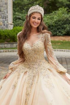 Modest quinceañera ball gown has a gorgeous illusion neckline designed with glam crystal beaded lace appliqués that cascade down the bodice to the shimmering sparkle tulle skirt and adorn the sheer bishop sleeves that leads to a breathtaking tied keyhole back. Champagne Quinceanera Dresses, Beaded Corset