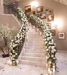 a staircase decorated with white flowers and greenery next to lit candles on the floor