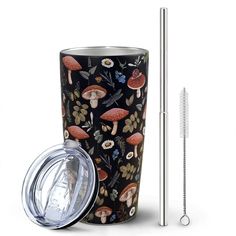 the tumbler cup has a straw in it and is decorated with mushrooms, leaves, and flowers