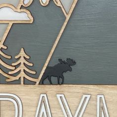 a wooden sign that says day with a moose in the background