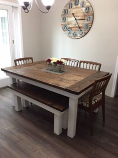 a dining room table with benches and a clock on the wall