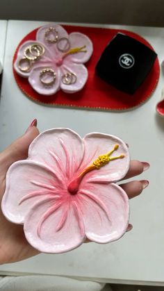 a person holding a pink flower in front of a table with other items on it