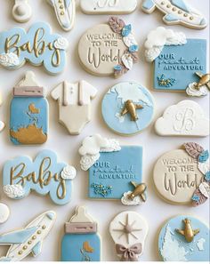 baby shower cookies with blue and white icing are arranged on a table in front of the words welcome to the world