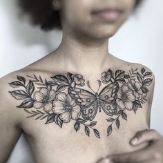 a woman's chest with flowers and a butterfly tattoo on her left side shoulder