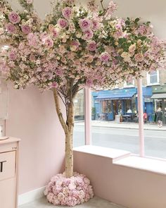 a tree with pink flowers in front of a window