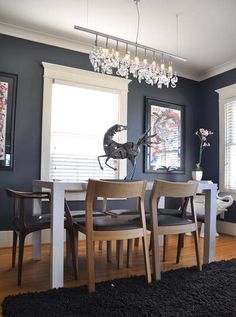 a dining room table with four chairs and a chandelier hanging from the ceiling