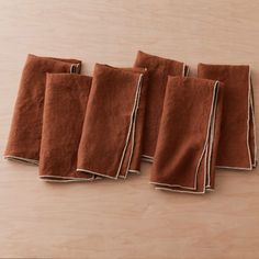 five brown linen napkins are lined up on a table