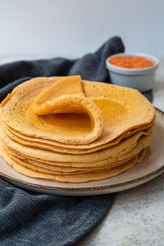 a stack of tortillas on a plate with some dipping sauce