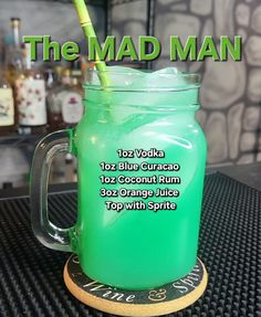 there is a green drink with a straw in it on top of a coaster that says the mad man