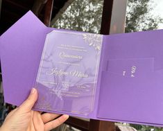 a person holding up a purple wedding card