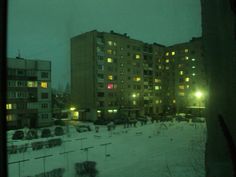 an apartment building is lit up at night in the snowy city with snow on the ground