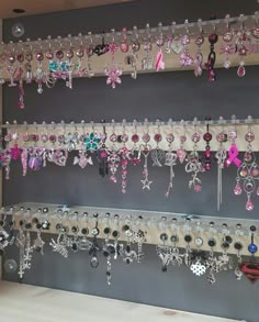 a wall mounted jewelry rack filled with lots of pink and white earrings hanging from it's sides