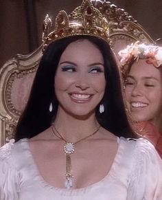 two women wearing crowns and smiling for the camera