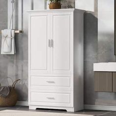 a bathroom with a white cabinet next to a mirror and towel dispenser