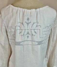 the back of a white blouse with embroidered designs on it