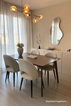 a dining room table with four chairs and a vase on top of it in front of a window