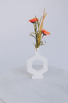 a white vase with flowers in it sitting on a table