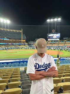 a baseball player standing in the middle of a stadium with his arms crossed and looking down