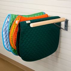 a green purse hanging from a hook on a white garage door with four different colors of quilts