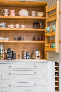 a kitchen cupboard filled with lots of different types of cups and saucers on top of wooden shelves