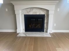 an empty living room with a fireplace and hard wood floors