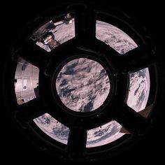 the earth seen through a porthole window in outer space, looking down on clouds and blue sky