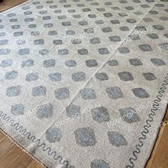 an area rug with blue and gray dots on it in a room that has wooden floors