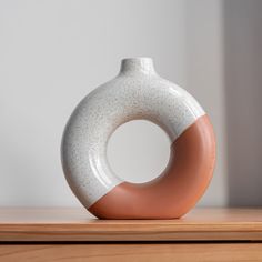 a white and brown vase sitting on top of a wooden table