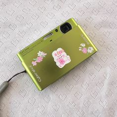 a green cell phone sitting on top of a white table cloth next to a charger