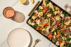 a table topped with a tray of food next to a glass of orange juice and a fork