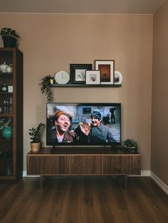 a flat screen tv sitting on top of a wooden entertainment center in a living room