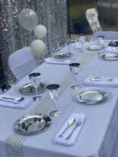 the table is set with silver plates and silver napkins for an elegant dinner party