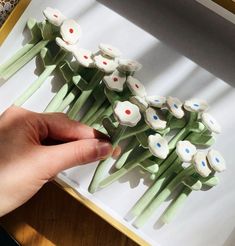 a hand is reaching for some cake like flowers on a tray with white and blue icing