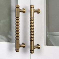 two brass door handles on white doors with mirror in the backgroung area